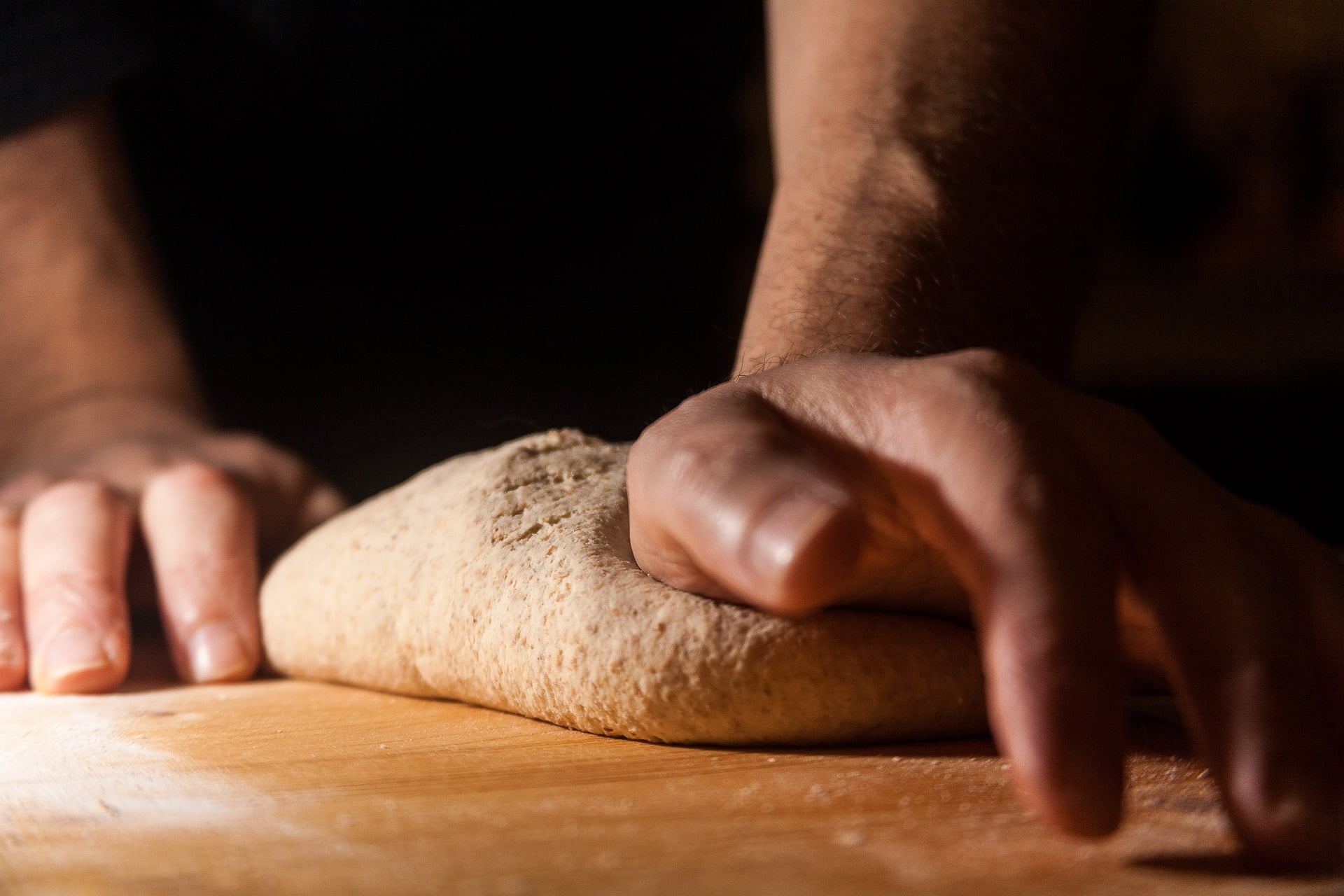 Close-up of two hands kneading bread dough