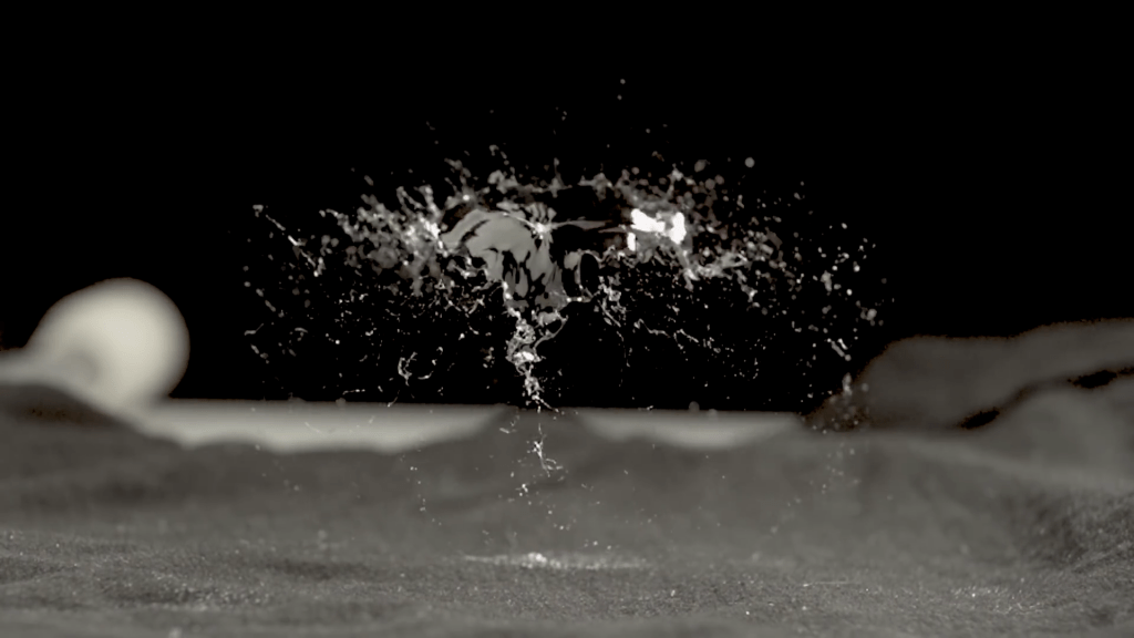 A bacteria-filled bubble bursts to create a spray of droplets.