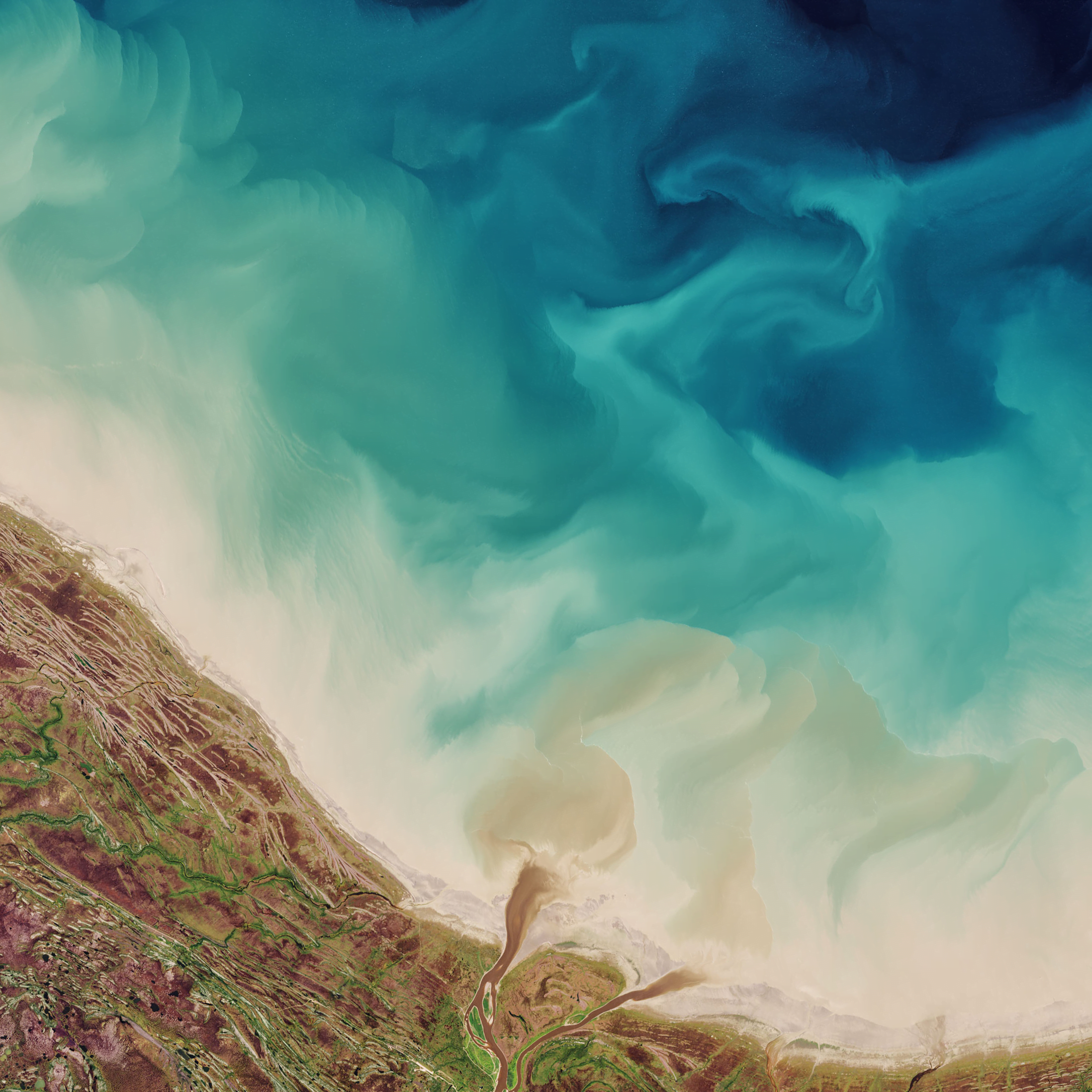 Sediments swirl along the coast of the Hudson Bay.