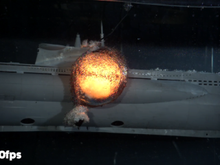 An expanding explosion bubble from a depth charge placed near a model submarine.