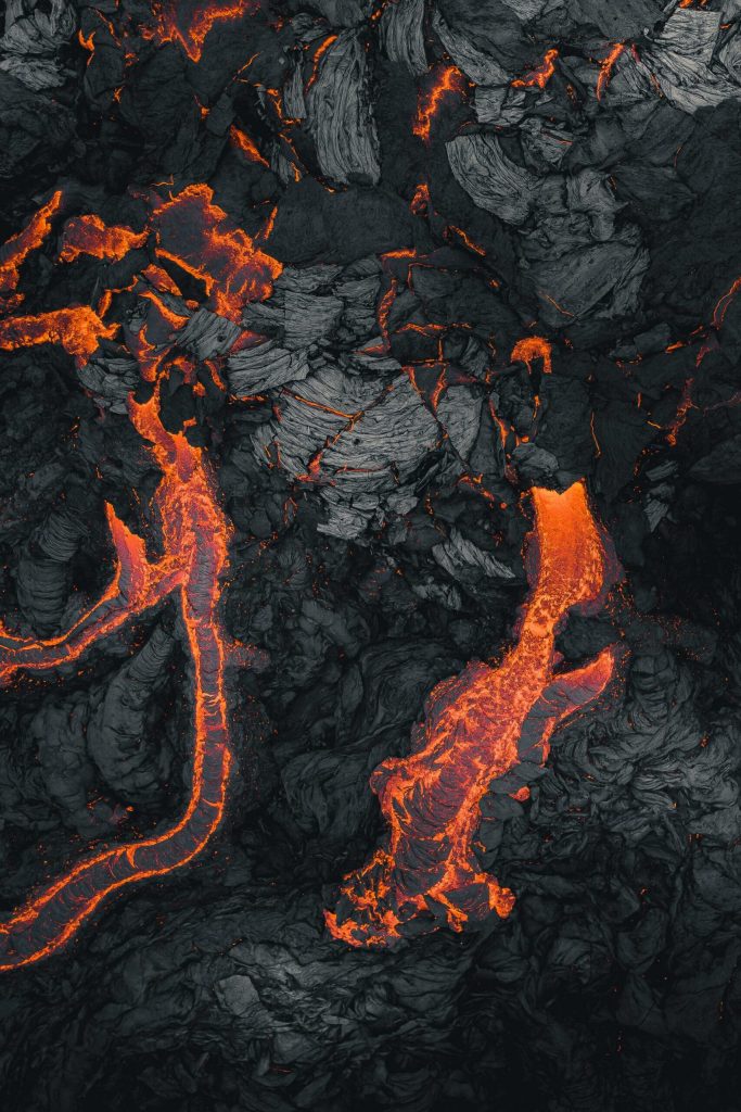 Orange lava stripes cross the black of cooling rock. Orange lava stripes cross the black of cooling rock.