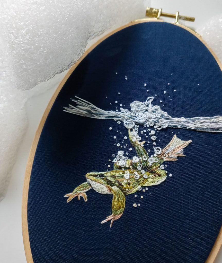 A frog jumps into water in this thread-painted embroidery. A frog jumps into water in this thread-painted embroidery.