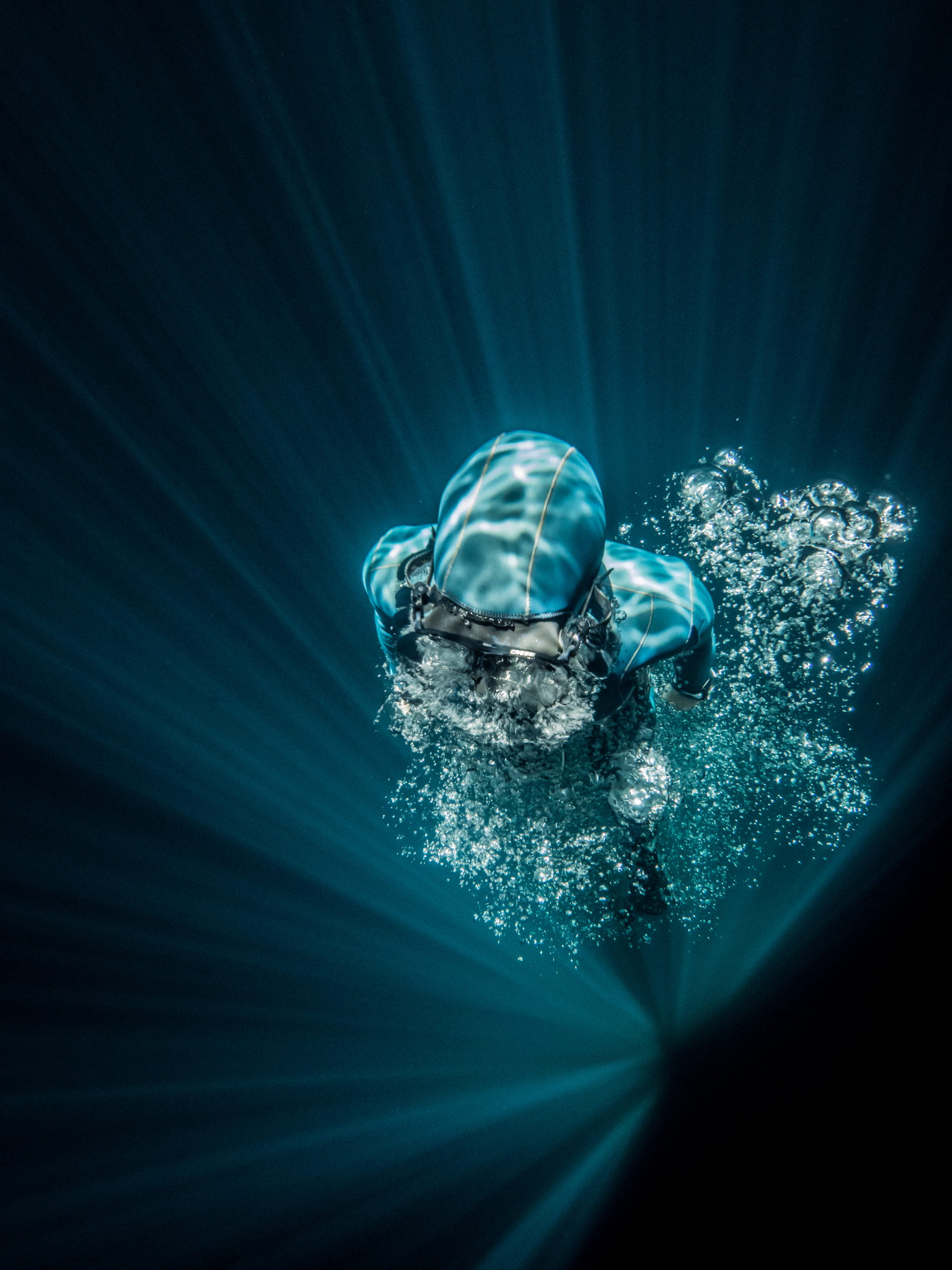 A freediver emerges through a plume of bubbles.
