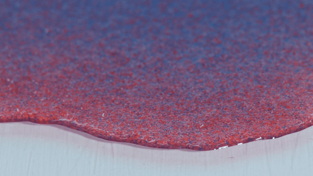 Close-up shot on clear silicone oil with a suspension of large red glass particles and smaller blue glass particles. Close-up shot on clear silicone oil with a suspension of large red glass particles and smaller blue glass particles.