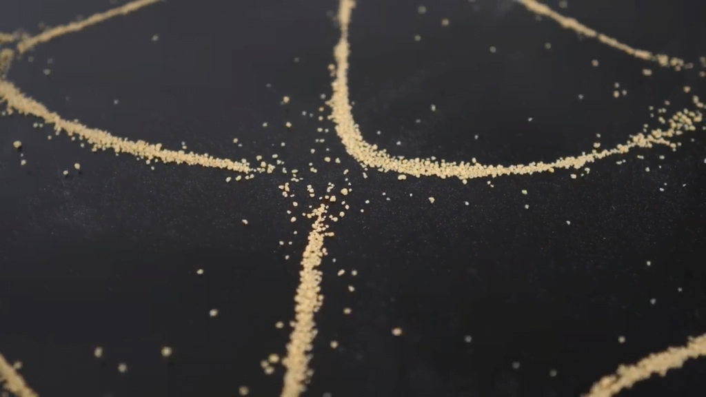 Close-up view of sand vibrating on a Chladni plate.