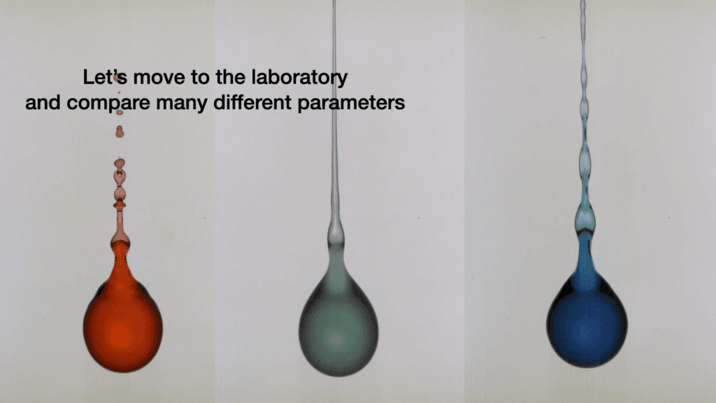Composite image of three droplets detaching from (unseen) strings. On the left, a red droplet with many secondary droplets forming on its tail. In the middle a green droplet with a long, smooth tail jet. On the right, a blue droplet with a long tail that repeatedly expands and contracts in radius without breaking. Text reads, &quot;Let&#039;s move to the laboratory and compare many different parameters.&quot;