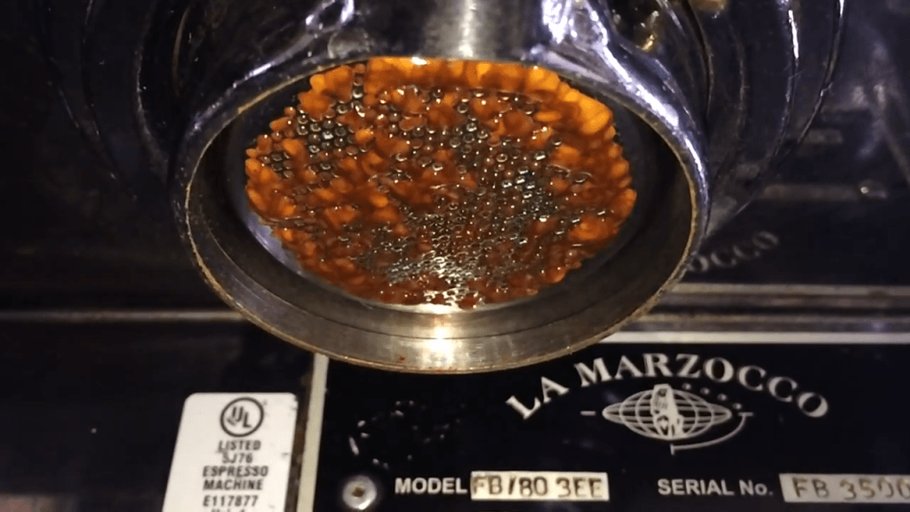 Espresso being squeezed through an industrial espresso maker.