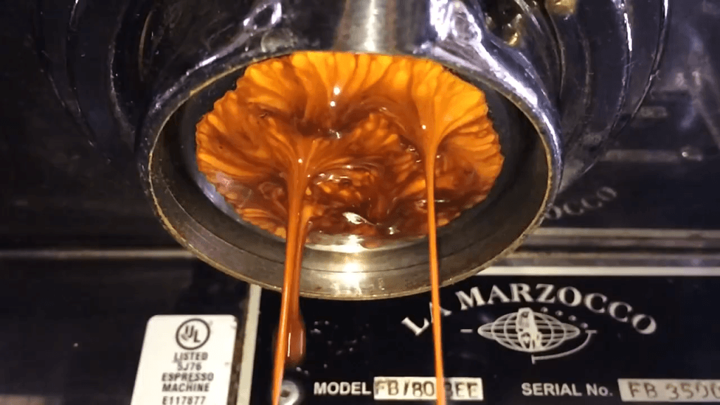 Espresso being squeezed through an industrial espresso maker.