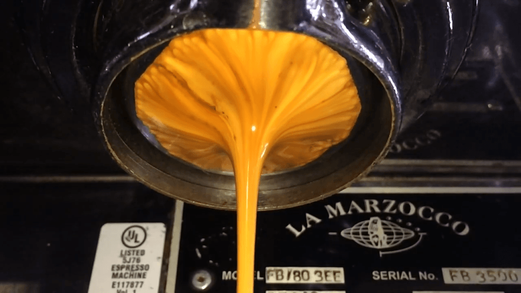 Espresso being squeezed through an industrial espresso maker.