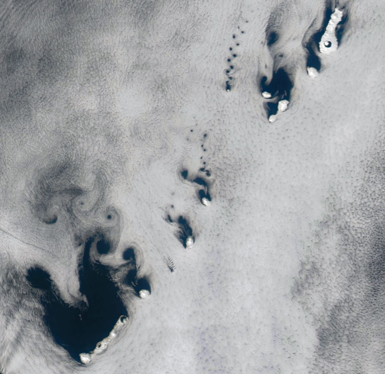 A satellite image of the Kuril Islands shows vortex streets extending downstream of each island.