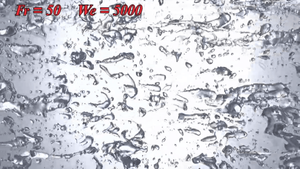 At Fr = 50 and We = 5000, the bubbles are small, scattered, and distorted.