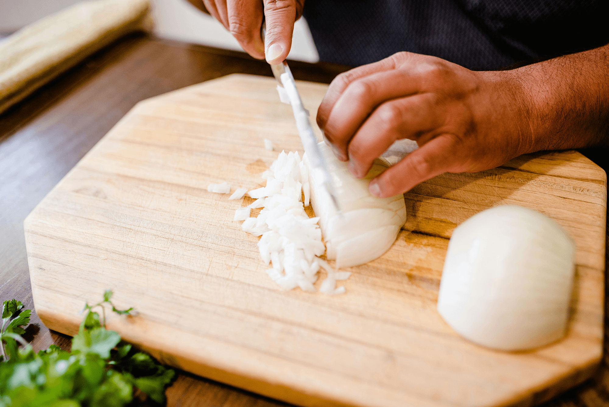 A person cutting an onion on a cutting board.