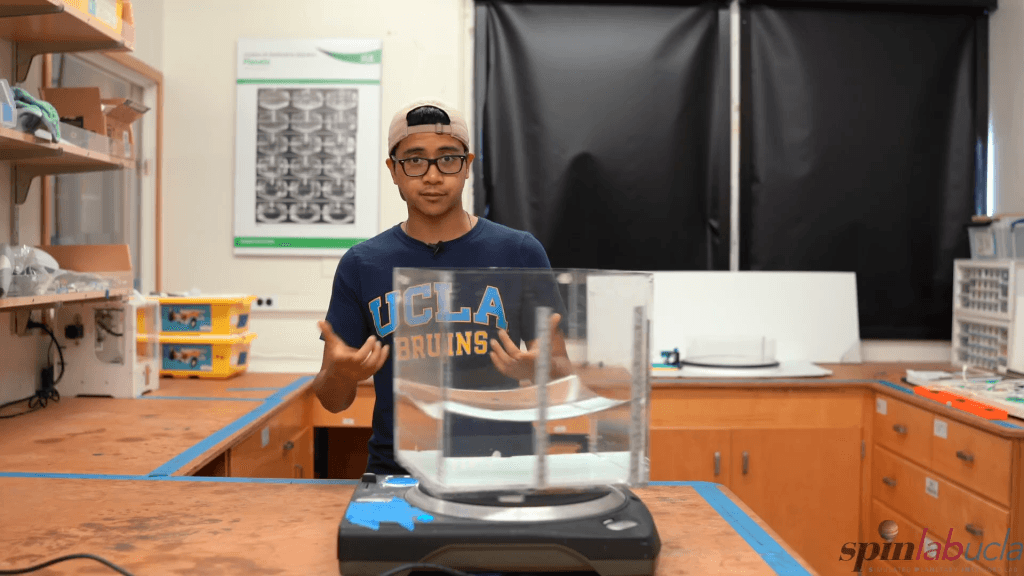 A tank of water rotating on a DJ turntable takes on a curved, paraboloid shape. A tank of water rotating on a DJ turntable takes on a curved, paraboloid shape.