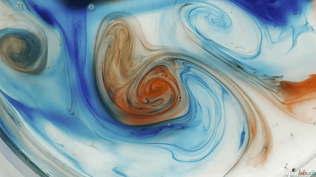 Top-down view of red and blue dyes swirled together in a rotating tank. Top-down view of red and blue dyes swirled together in a rotating tank.