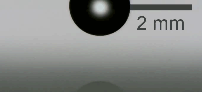 A droplet splashes against a flat surface.