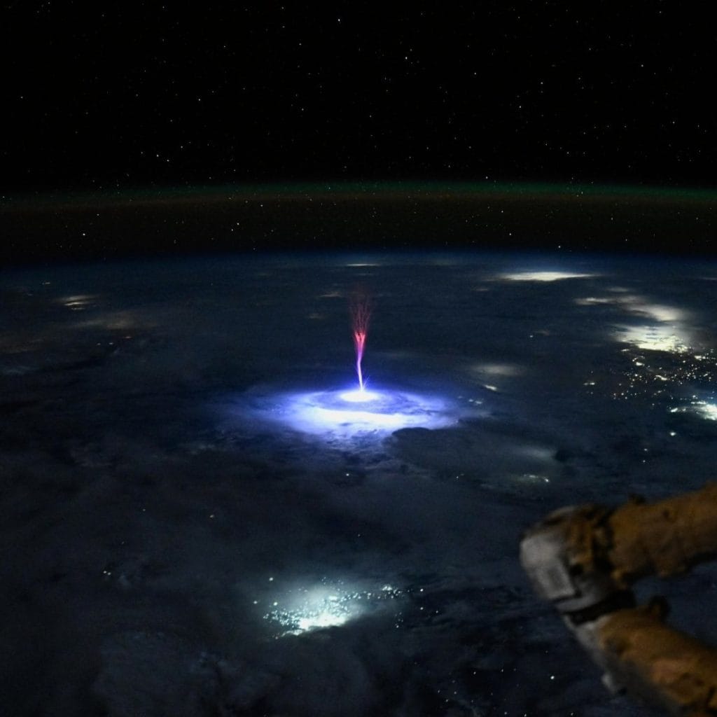 An astronuat photo of a red sprite -- a plasma outburst from a thundercloud -- as viewed from orbit.