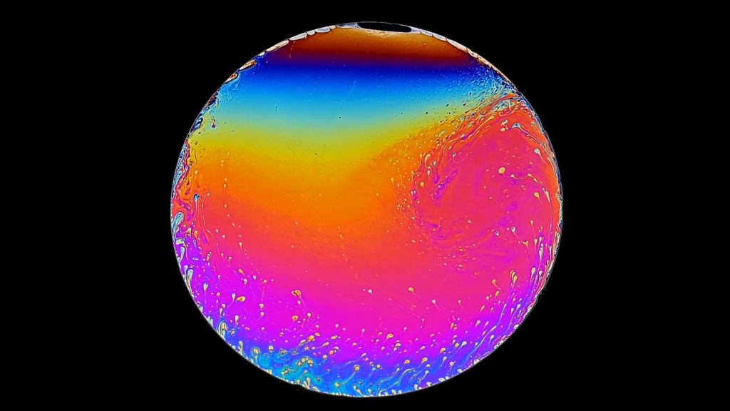 A slowly draining soap film, illuminated to show its interference colors.