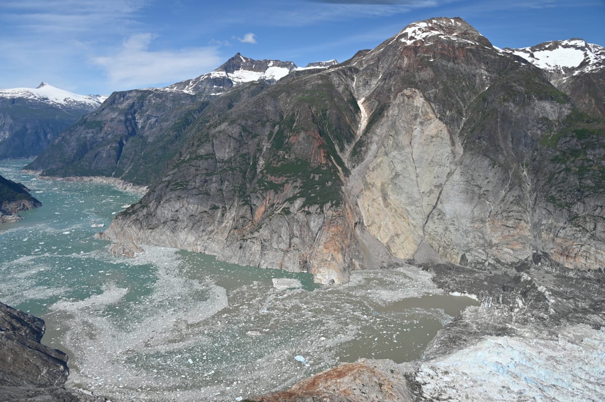 An image showing the aftermath of the 10 August, 2025 landslide in Alaska's Tracy Arm Fjord, which caused the second largest tsunami recorded. The light rock slope shows where material fell from. On the lower right, the foot of the South Sawyer Glacier is just visible.